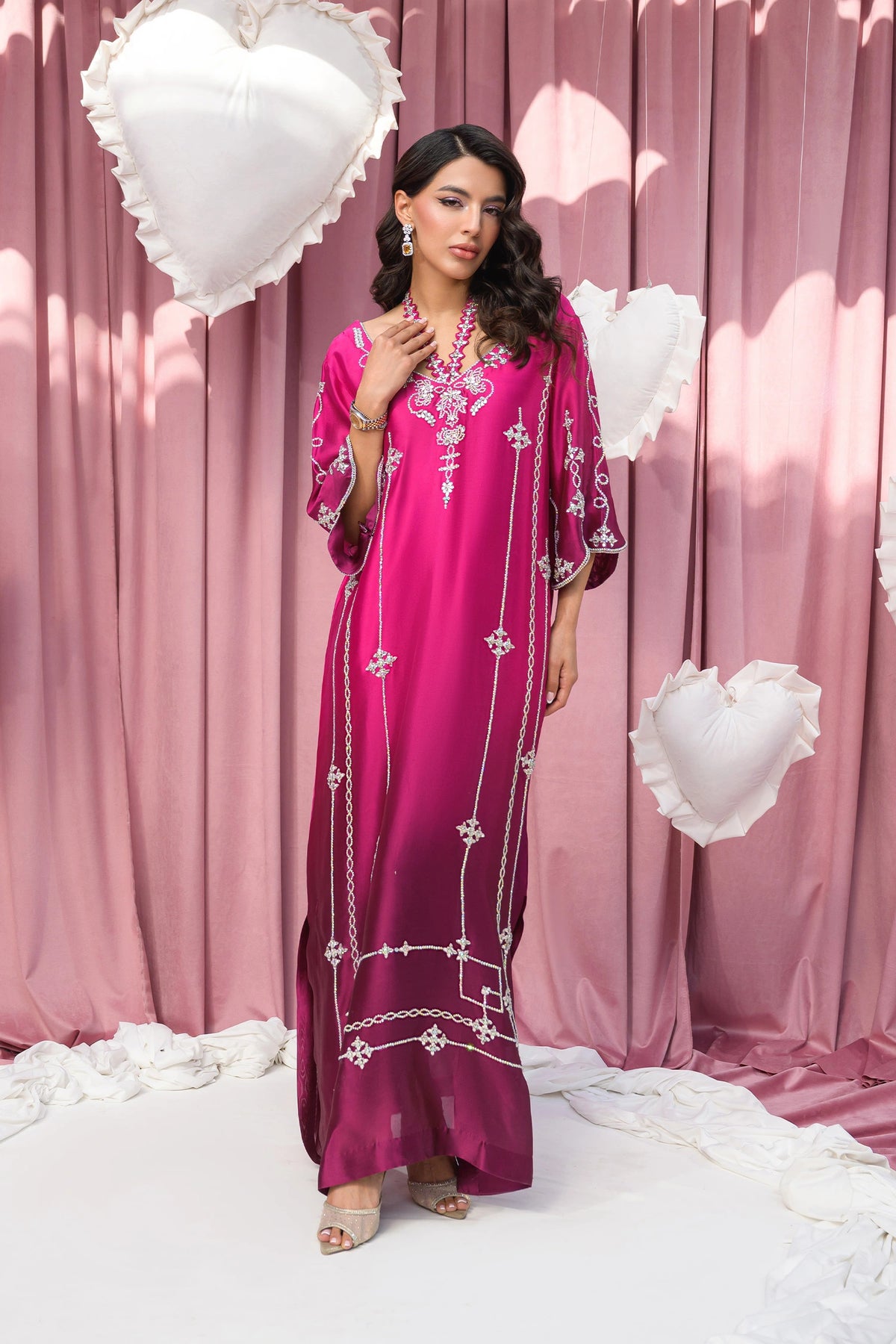 Full-length view of a model in a magenta silk kaftan dress with silver embroidery.
