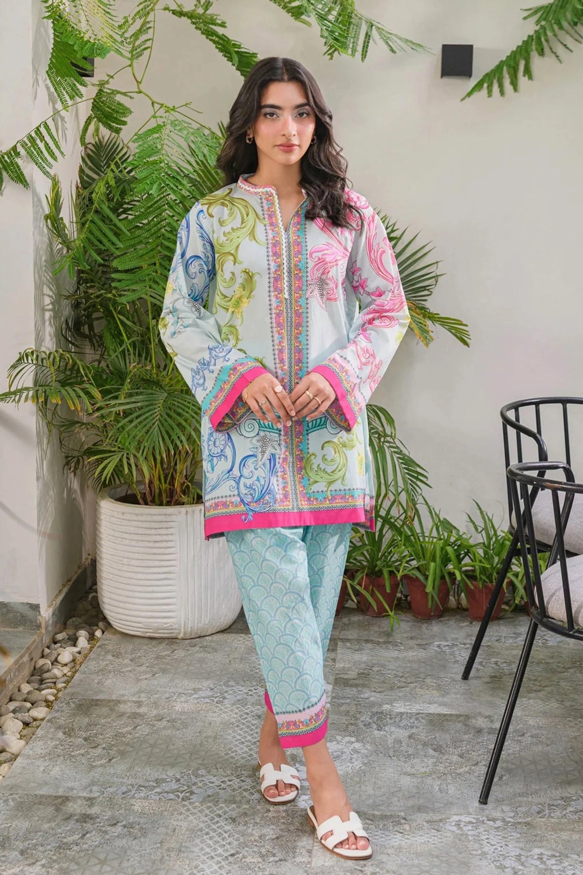 Model wearing a light blue 2-piece lawn suit with colorful baroque prints, pink borders, and matching pattern trousers.
