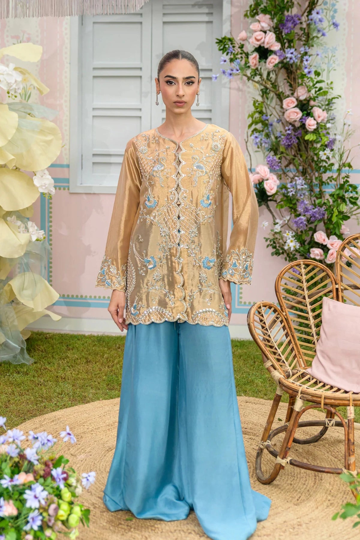 Model wearing an embroidered gold shirt with blue palazzo pants.

